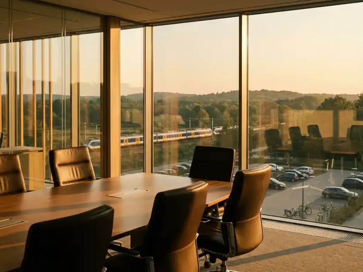 Welke vergaderlocaties in de Utrechtse Heuvelrug zijn goed bereikbaar per OV en auto? Moderne vergaderzaal met leren stoelen rond houten tafel, uitzicht op Utrechtse Heuvelrug met trein in landschap